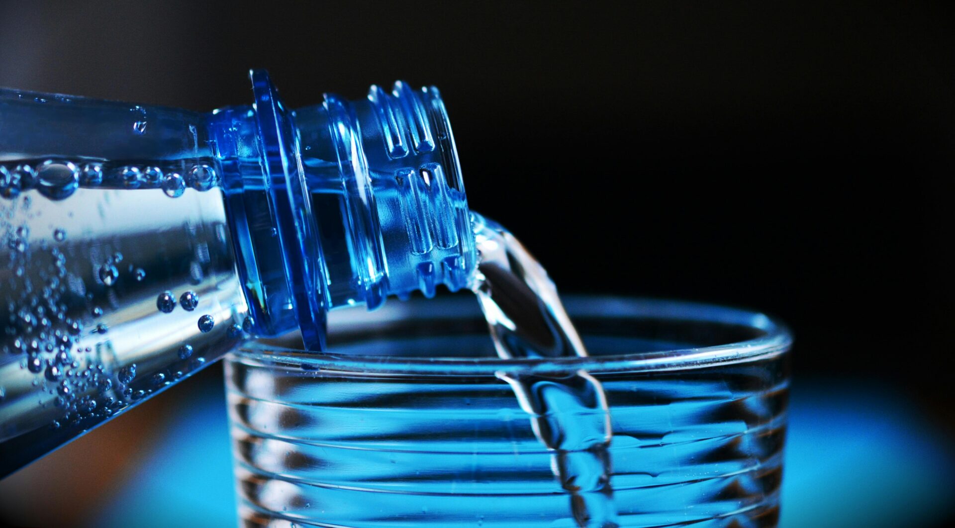 Nahaufnahme Der Flasche, Die Wasser Auf Glas Gießt